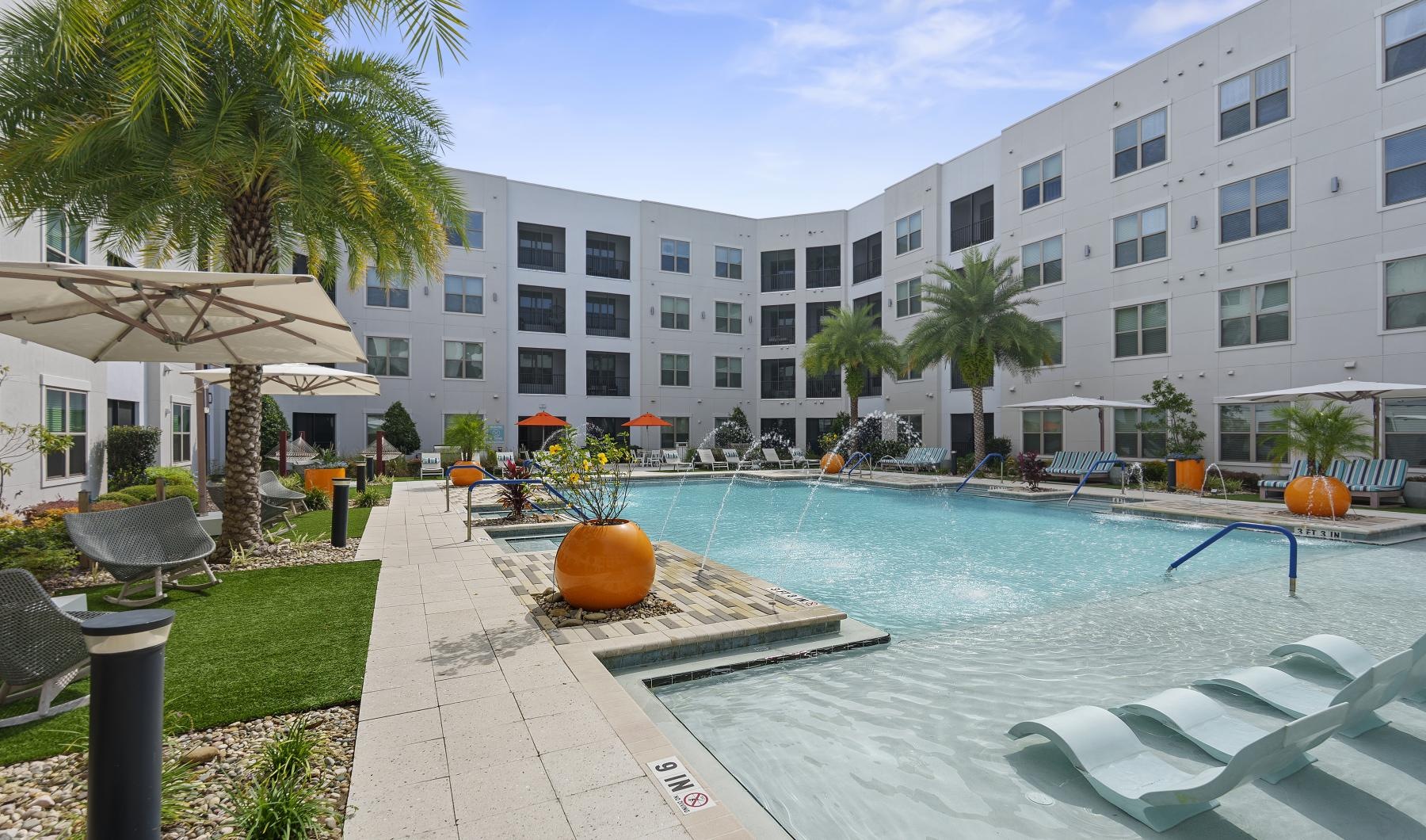 a pool with chairs and umbrellas by a building