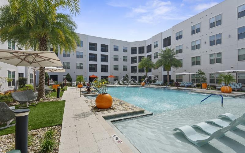 a pool with chairs and umbrellas by a building